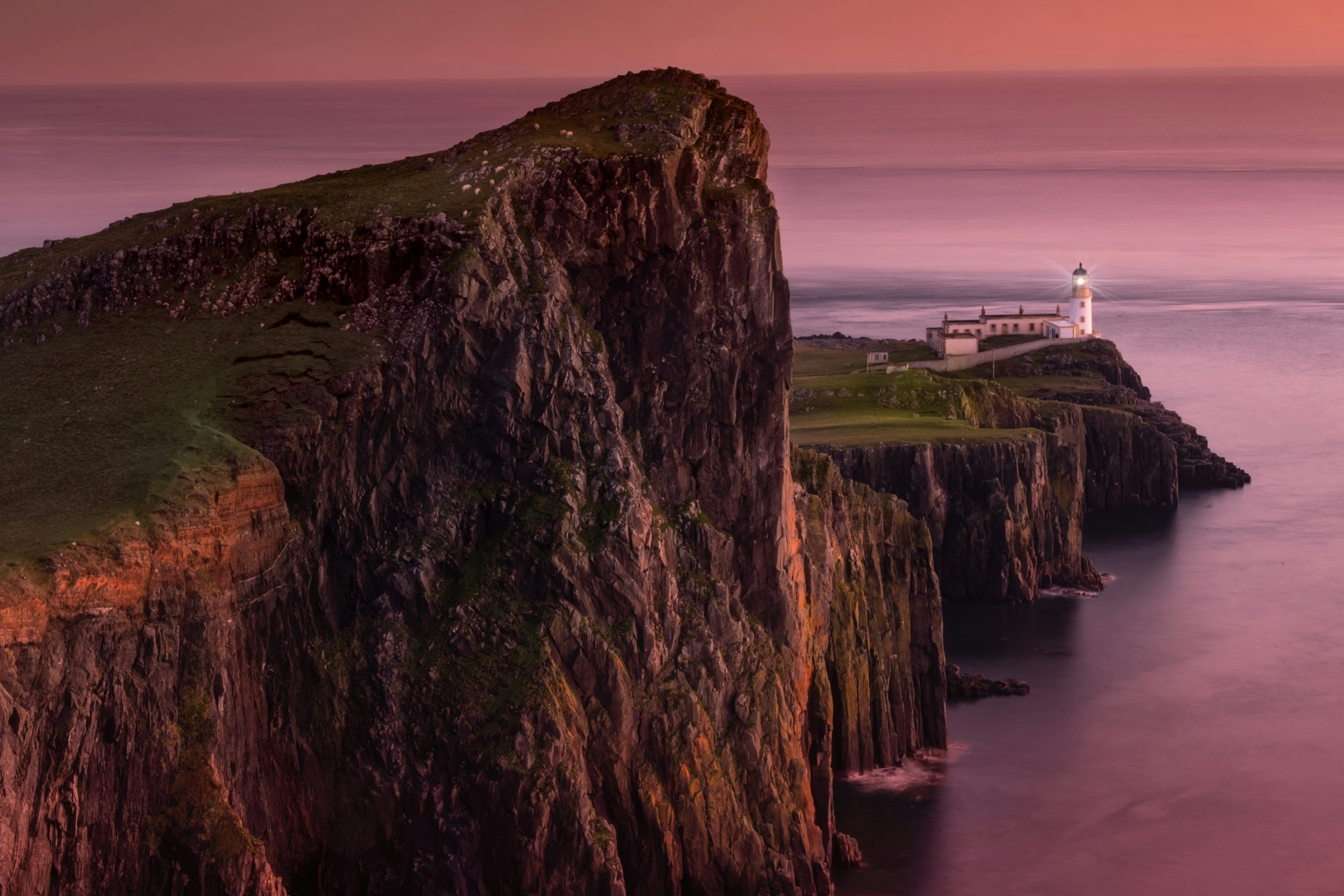 Neist Point lighthouse on a green cliff above the Atlantic
